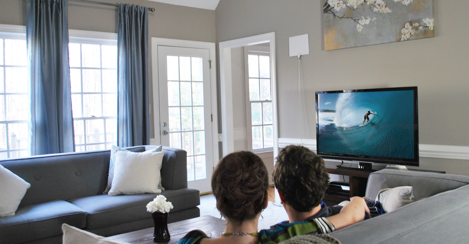 man and woman sitting on couch watching TV in their living room