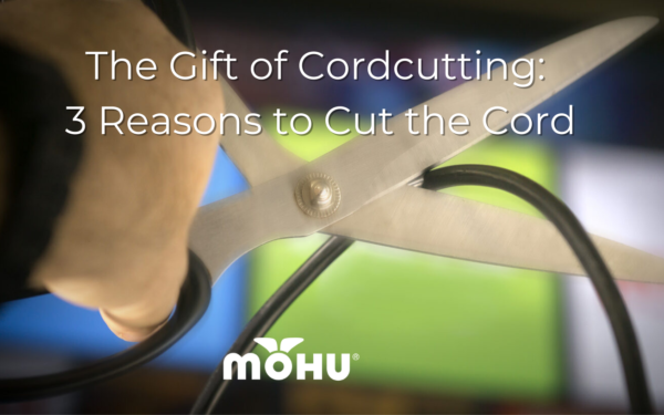 Hand holding scissors cutting cord, The Gift of Cordcutting: 3 Reasons to Cut the Cord