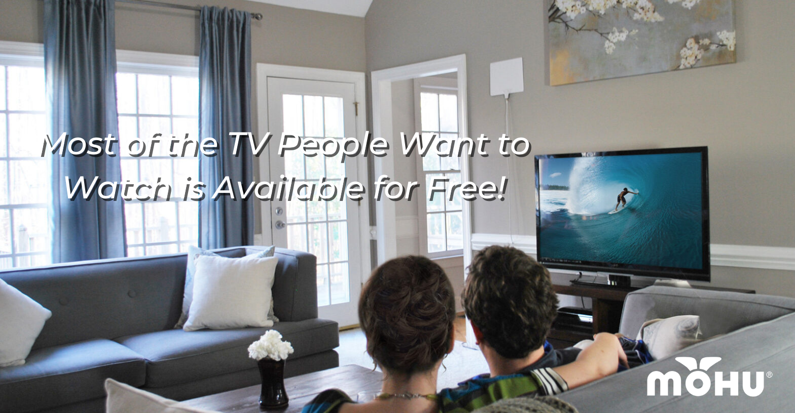 Couple sitting on the couch in front of a television with a Mohu antenna and the copy "Most of the TV People Want to Watch is Available for Free"