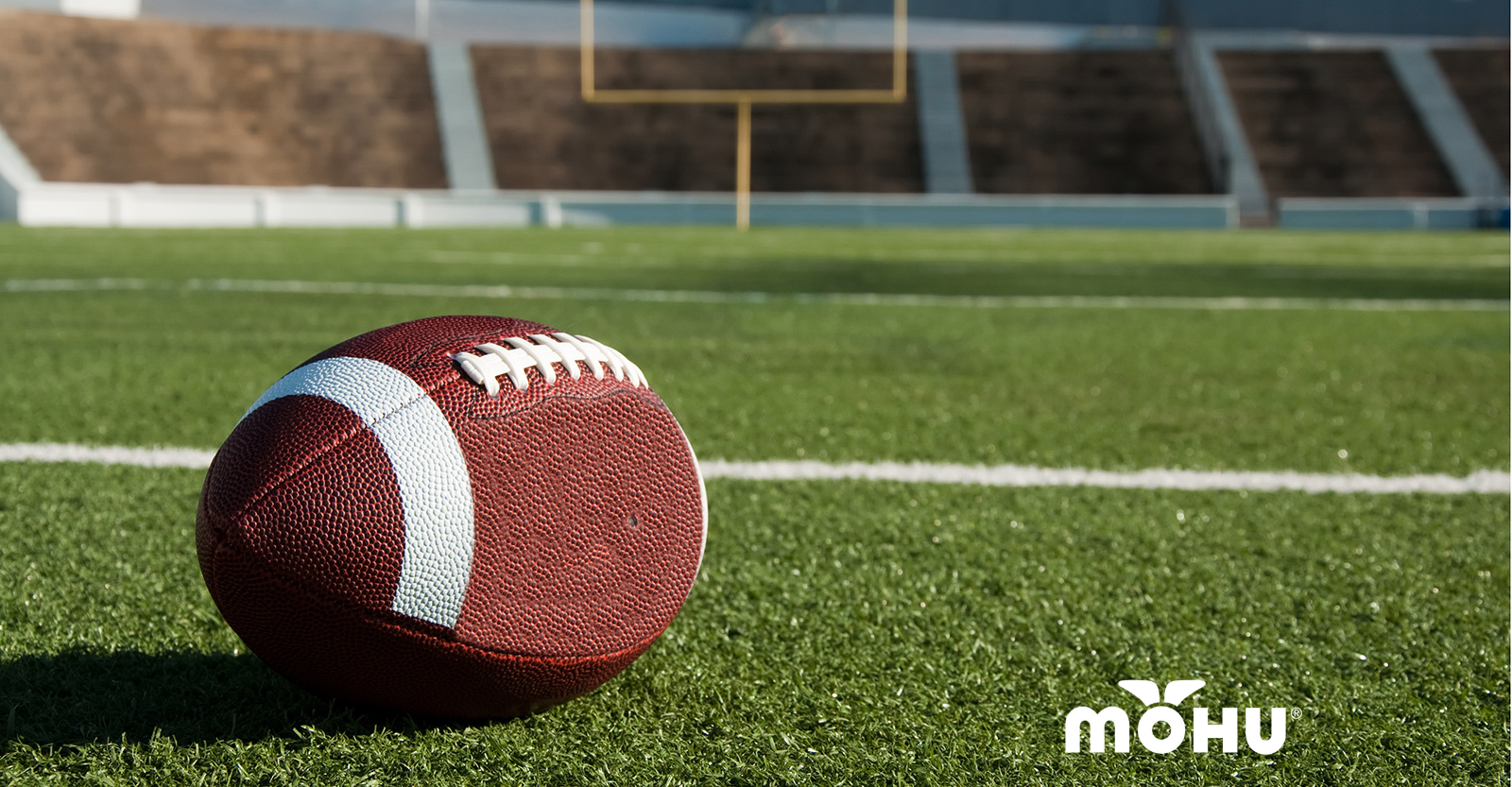 football resting on football field with stadium in background and mohu logo
