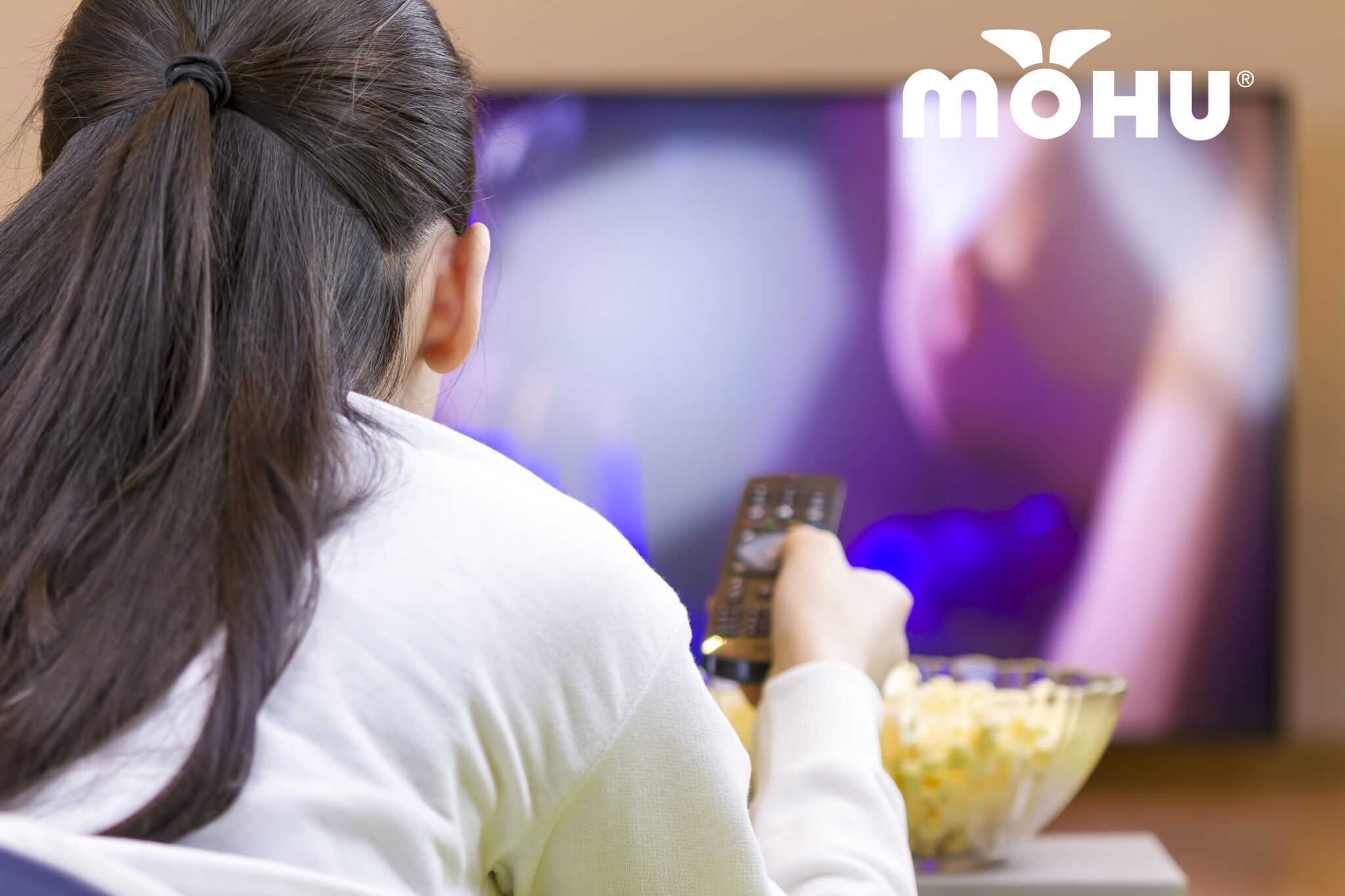 Girl watching TV with a bowl of popcorn and a mohu logo