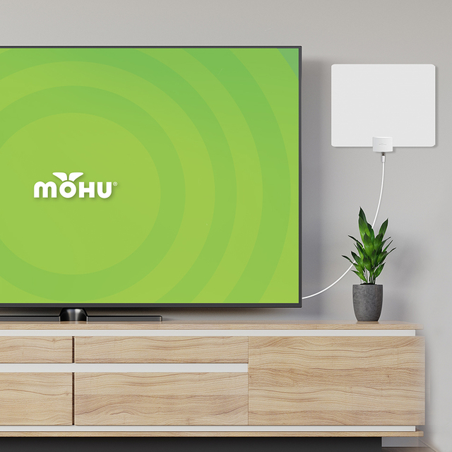 Mohu Leaf Plus TV antenna on wall next to TV with Mohu Logo